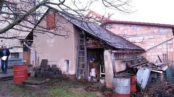 Stará hospodářská budova se žebříkem před opravou střechy Stará hospodářská budova se žebříkem před opravou střechy